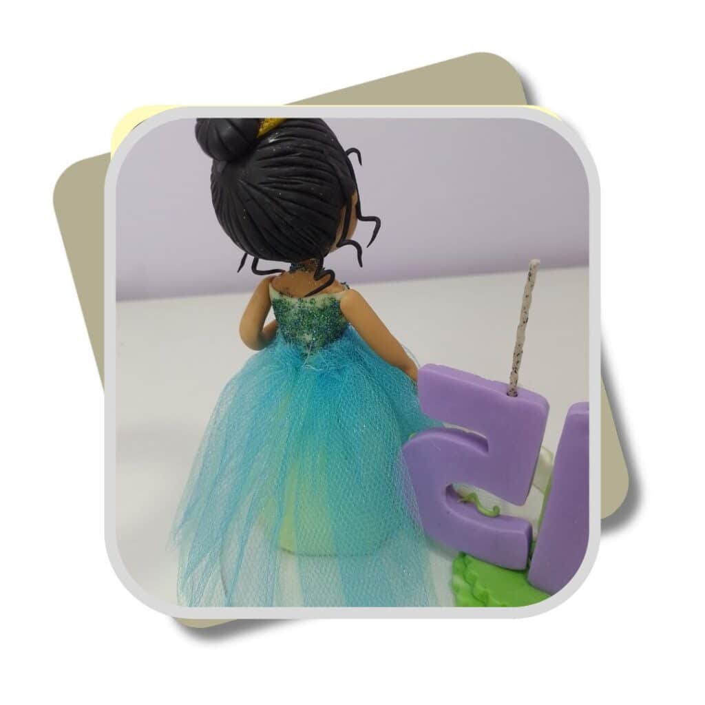Vista de costas da debutante de biscuit: coque, vestido verde-água e o número 15 lilás ao lado