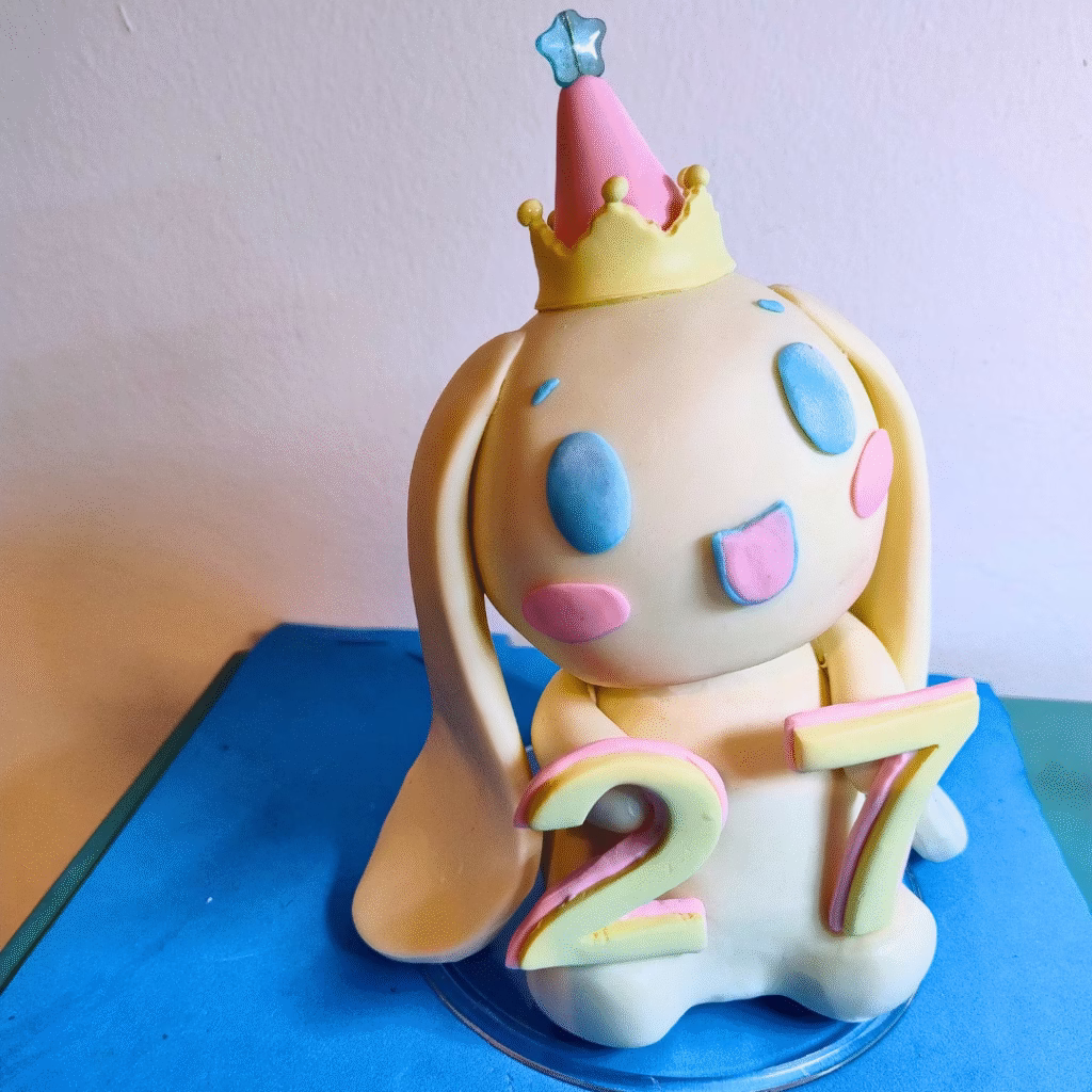 Cinnamoroll de biscuit com chapéu de festa, coroa e o número 27, em miniatura de aniversário