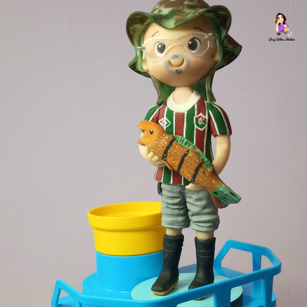 Miniatura de biscuit do torcedor de chapéu camuflado com a camisa tricolor e o peixe nas mãos