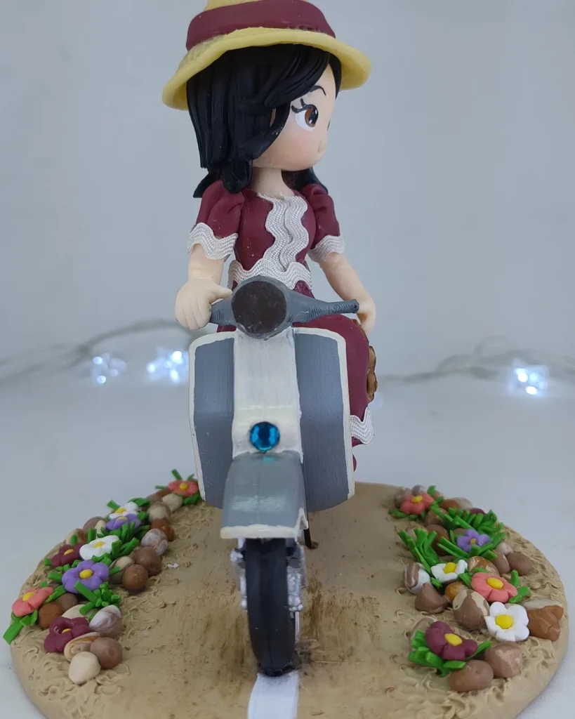 Boneca de biscuit de vestido vinho em scooter azul-clara, sobre base de flores
