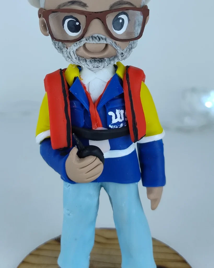 Miniatura de biscuit de idoso de colete vermelho e óculos, segurando ferramenta