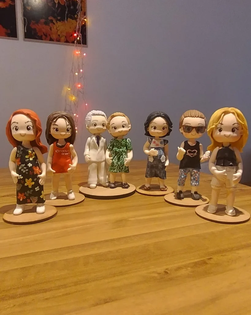 Sete miniaturas de biscuit da mesma família, cada uma com roupa diferente