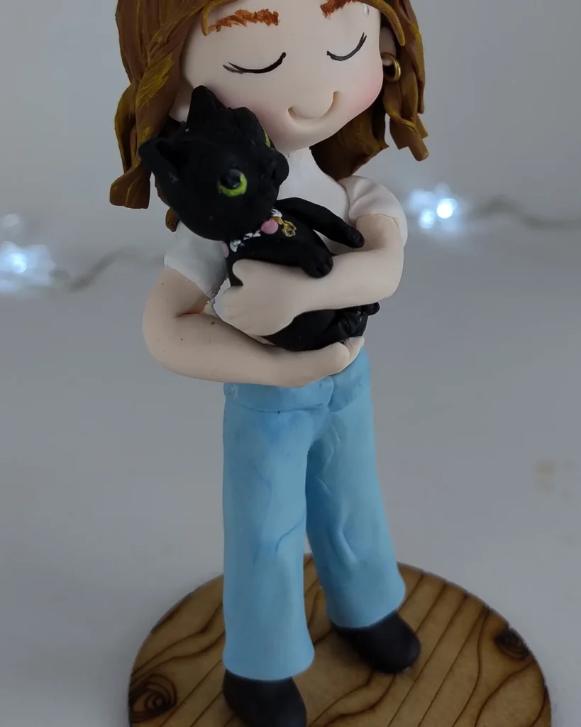 Miniatura de biscuit de menina abraçando seu gato preto no colo