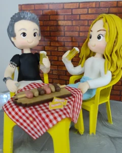 Casal de biscuit à mesa de bar com toalha xadrez, tábua de petiscos e copos de chope
