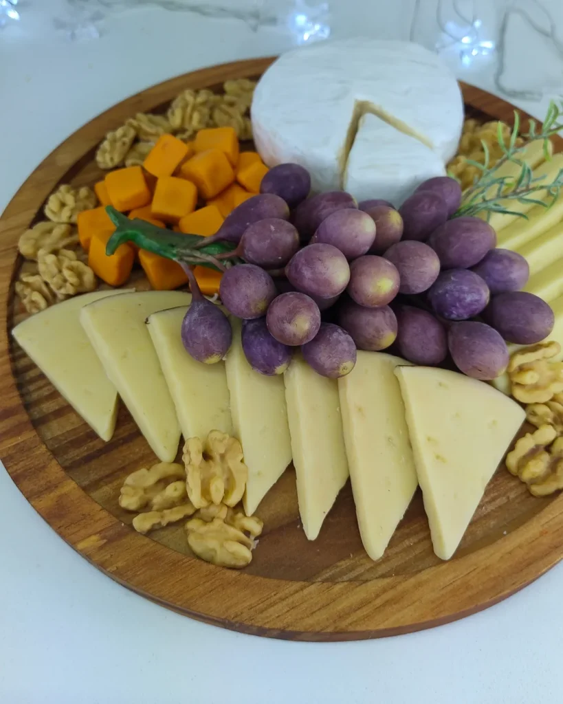 Comida cenográfica de tábua de frios em biscuit com queijos e uvas
